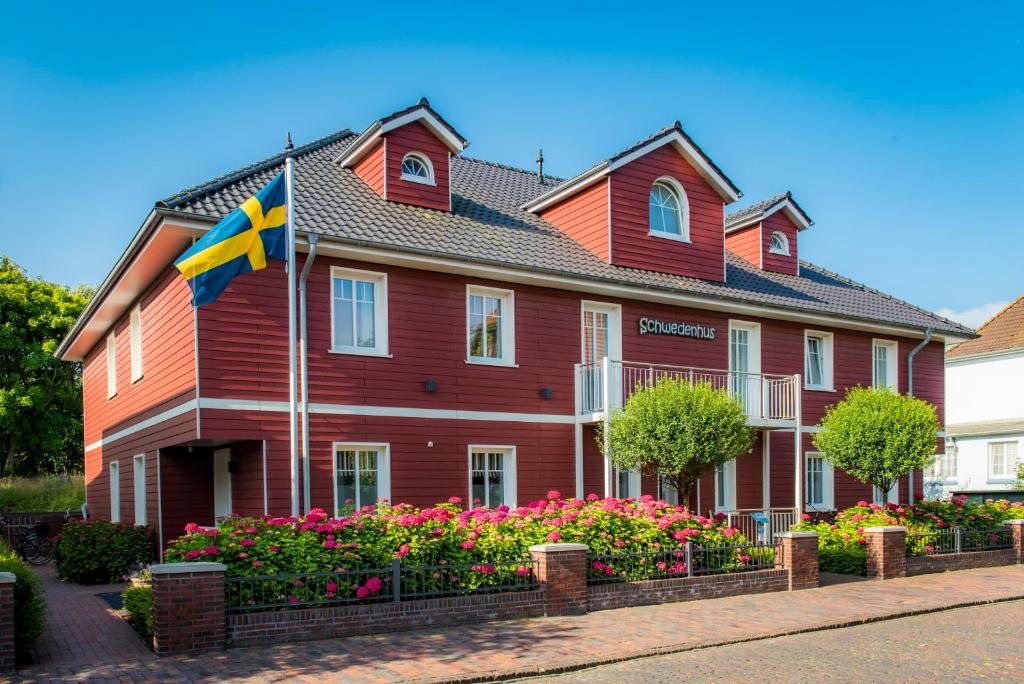 a red house with a flag in front of it at Schwedenhus in Wangerooge