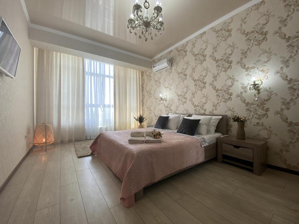 a bedroom with a large bed and a chandelier at Квартиры Le Majestic Lux возле Парка by Sutki26 in Pyatigorsk