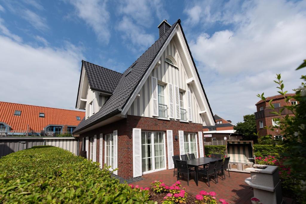 a house with a gambrel roof with a patio at Ferienhaus Strandhafer in Wangerooge