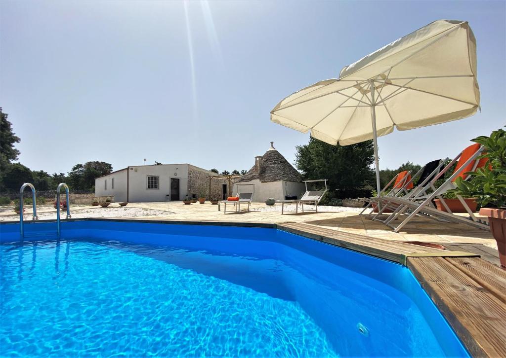 a pool with an umbrella and chairs and a house at WePuglia - Canto dei Grilli in Noci