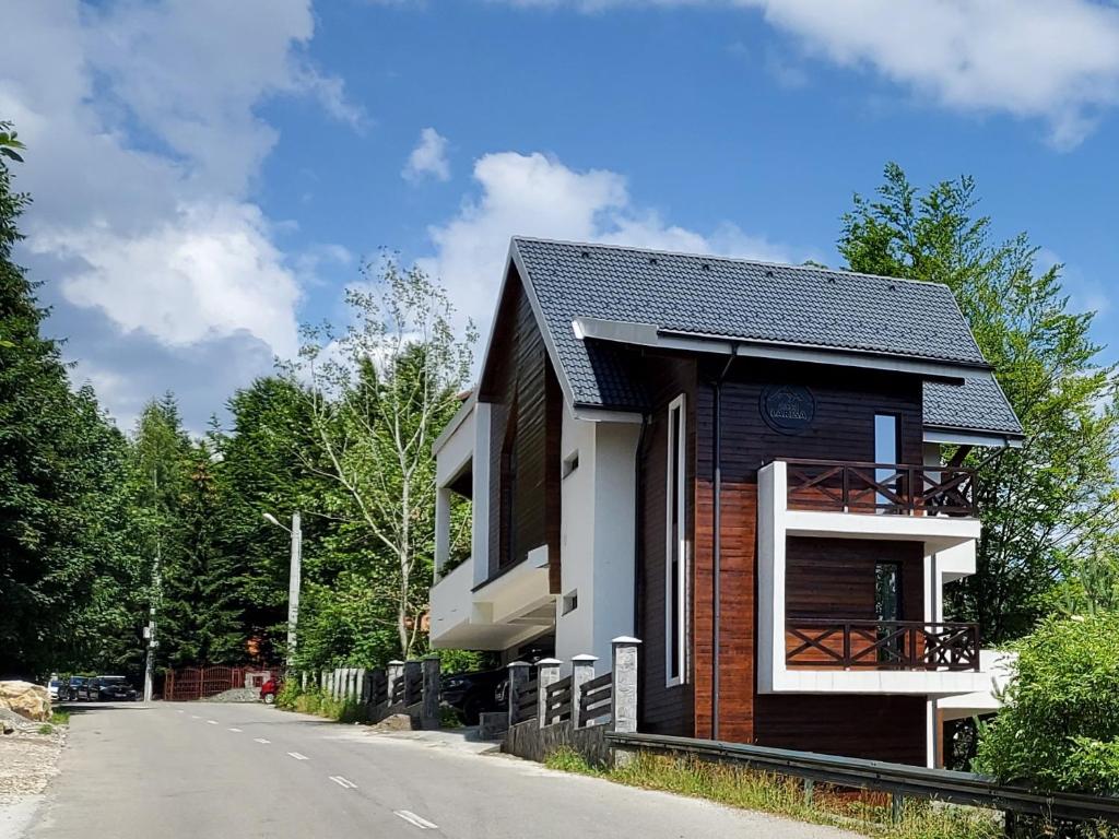 une petite maison sur le côté d'une route dans l'établissement Casa Larisa Apartments, à Sinaia