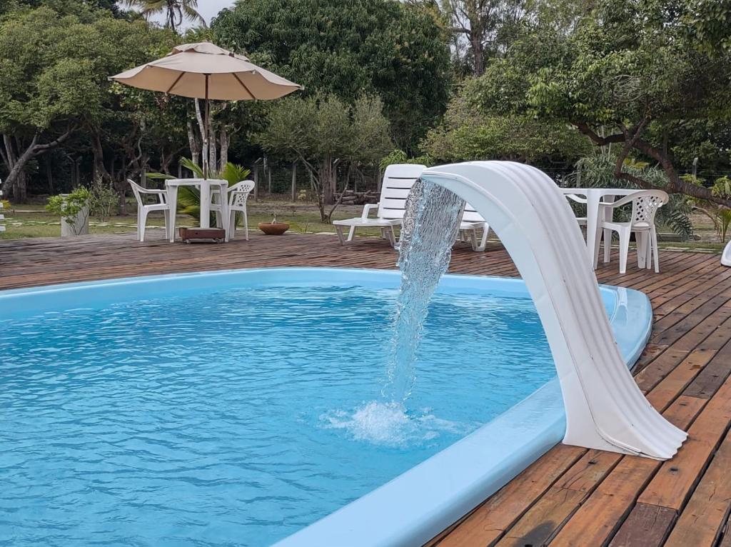 a water slide in a pool with an umbrella at Pousada Nossa Casa in Itaúnas