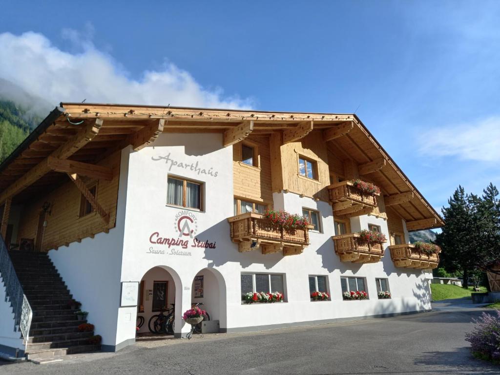 a building in the mountains with flowers on the balconies at Aparthaus Camping Stubai in Neustift im Stubaital