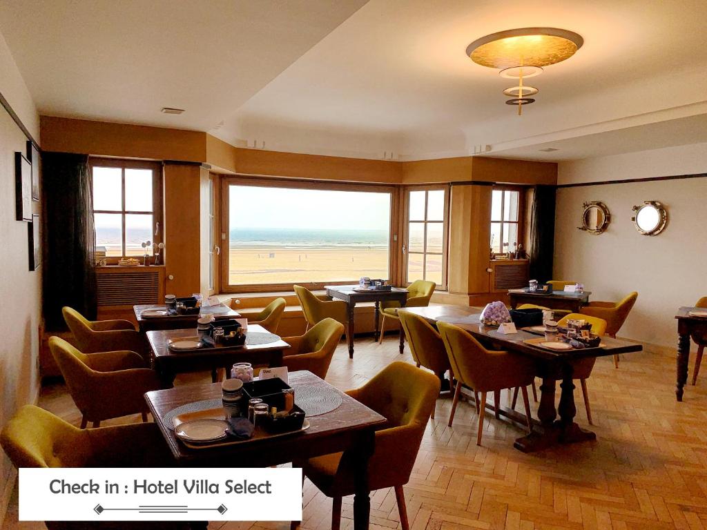 ein Restaurant mit Tischen und Stühlen und Blick auf den Strand in der Unterkunft Hotel Villa Escale in De Panne