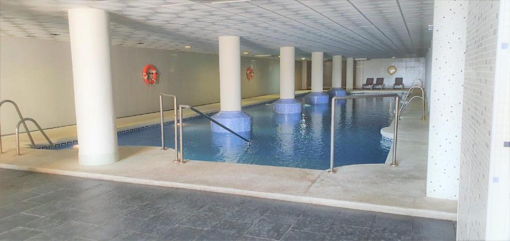 a swimming pool with columns and blue water in a building at La envia golf in Vícar