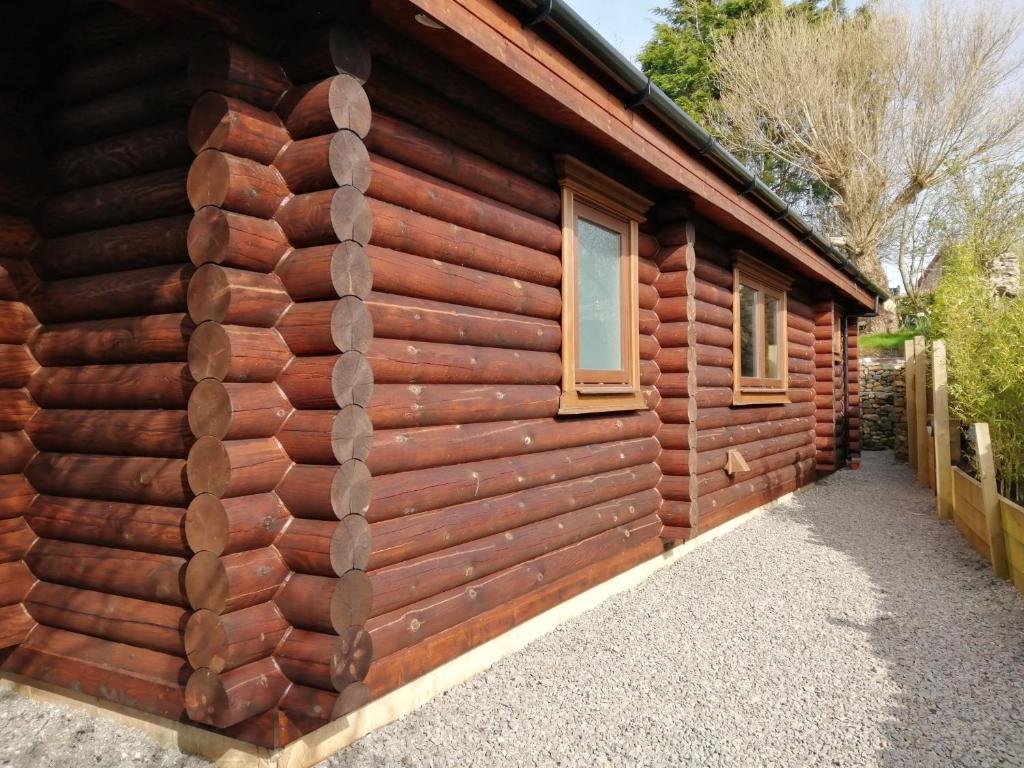 um lado de um chalé de madeira com duas janelas em Ravenglass Log Cabin em Ravenglass