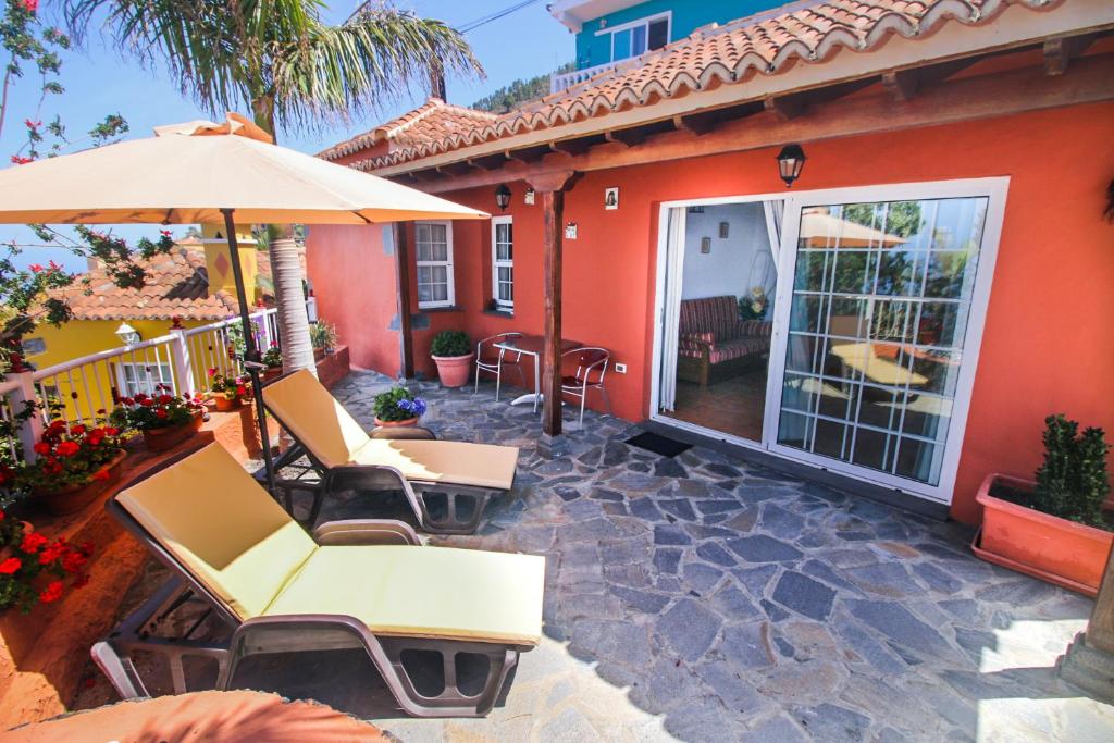 une terrasse avec des chaises et un parasol ainsi qu'une maison dans l'établissement Casas los Alisios, à Los Quemados