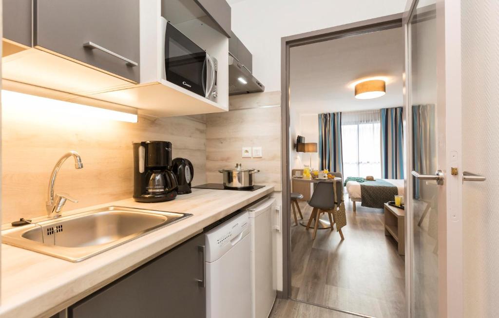 a small kitchen with a sink and a table at Résidence Odalys Archipel in La Rochelle