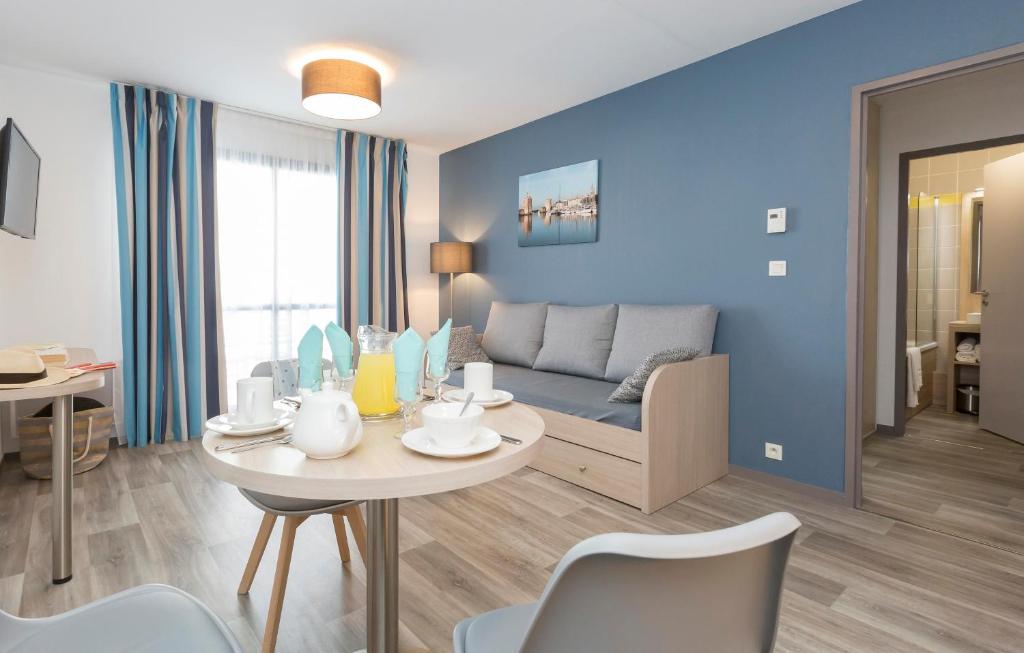 a living room with a couch and a table with chairs at Résidence Odalys Archipel in La Rochelle