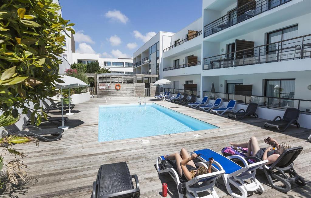 un grupo de personas tumbadas en sillas junto a una piscina en Résidence Odalys Archipel, en La Rochelle