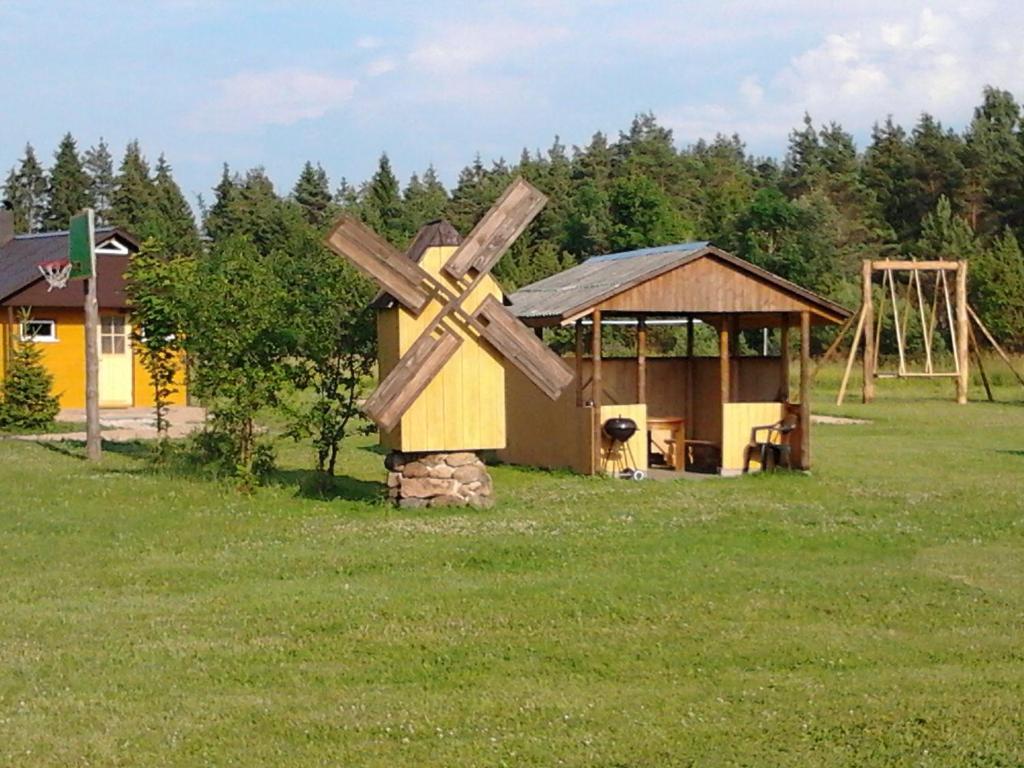 a large wooden windmill in a field with a playground at Laasi-Jaani Holiday Homes in Pamma