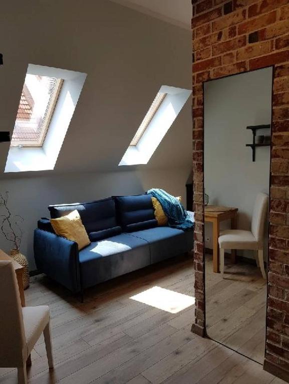 salon z niebieską kanapą i lustrem w obiekcie Loft Króla Kazimierza w Toruniu