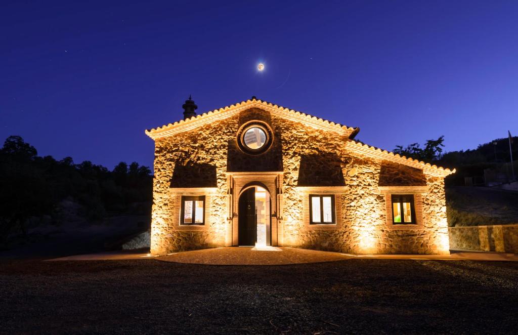 un bâtiment en pierre avec une horloge la nuit dans l'établissement Casa Rural Finca El Tornero, à Aracena