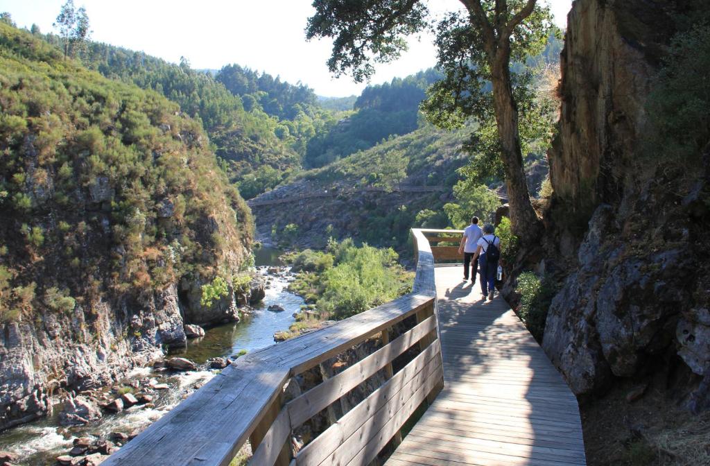 2 personnes marchant sur un pont au-dessus d'une rivière dans l'établissement Casa da Bichaca, à Castelo de Paiva