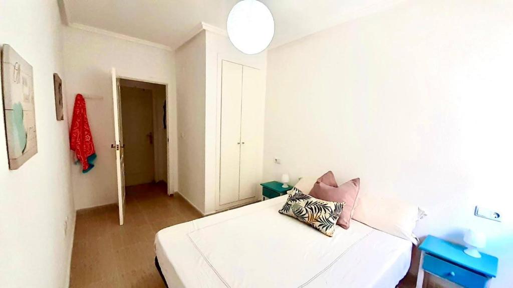 a bedroom with a white bed with pillows on it at 2 línea Cala del Palangre in Torrevieja