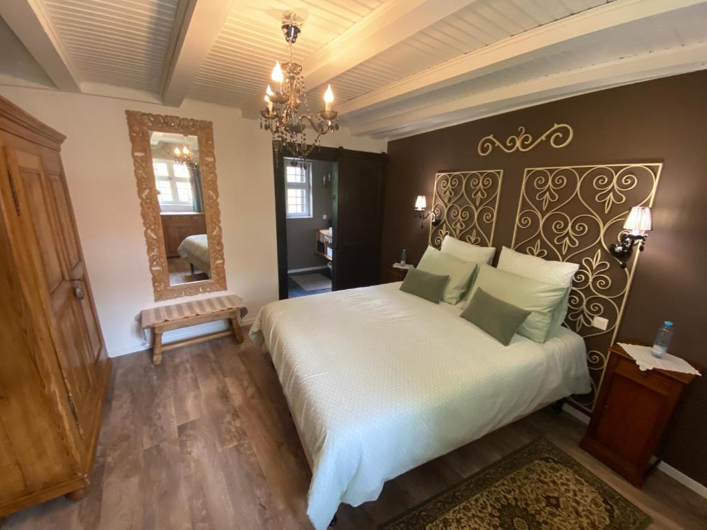 ein Schlafzimmer mit einem großen weißen Bett und einem Spiegel in der Unterkunft La Ferme de Grand Mère in Furchhausen