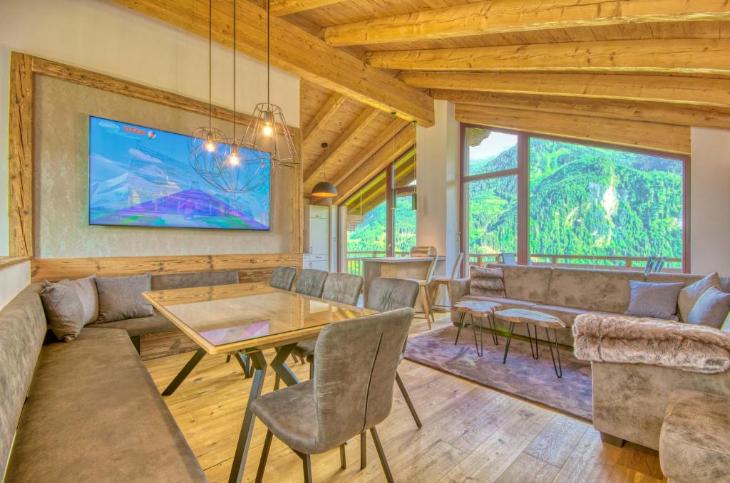 a living room with couches and a table and chairs at Ski-in Ski-out Chalet Maiskogel 17A - by Alpen Apartments in Kaprun