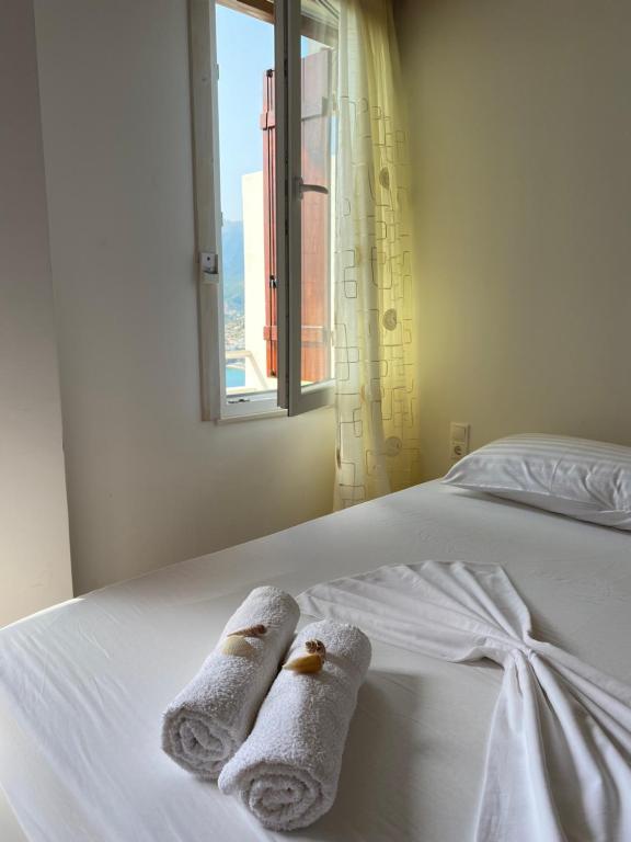 ein Schlafzimmer mit Handtüchern auf einem Bett mit Fenster in der Unterkunft Sunset Dream Guesthouse in Himarë