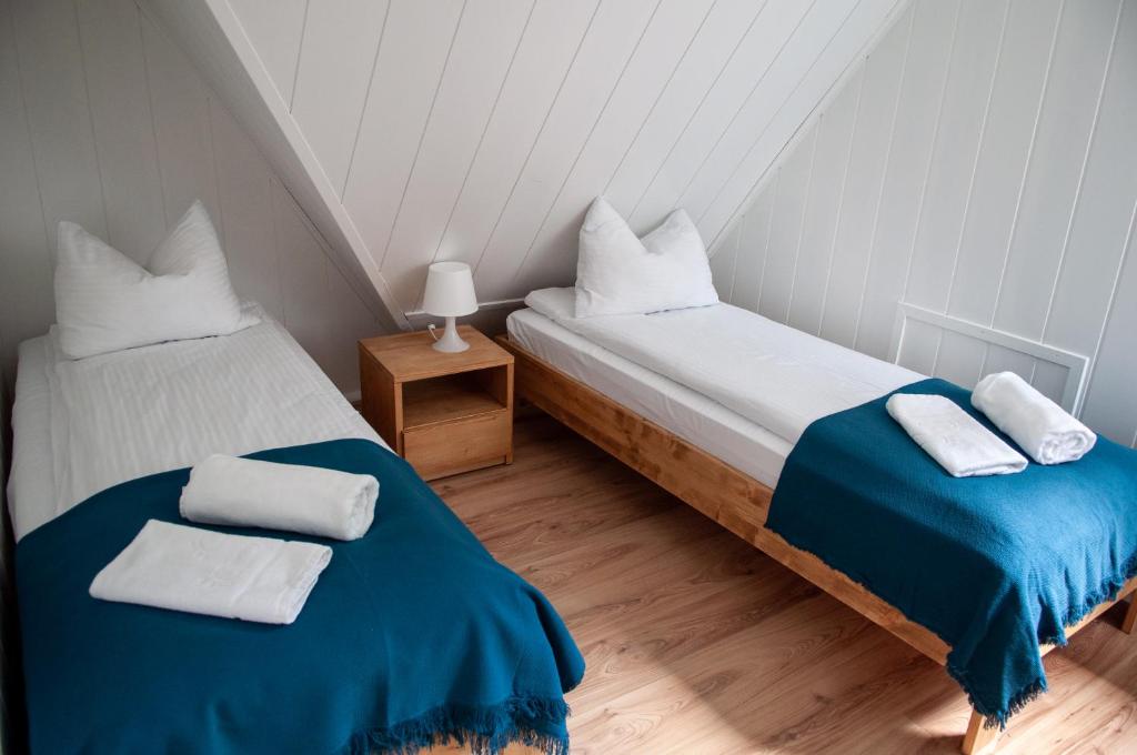 2 Betten in einem kleinen Zimmer mit blauer und weißer Bettwäsche in der Unterkunft Willa Monti in Szczyrk