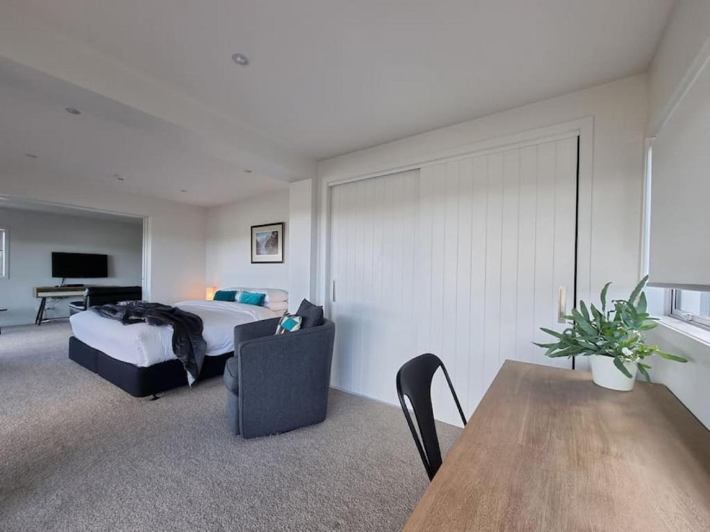a bedroom with a bed and a couch and a table at Fabulous Castor Bay 1 Bedroom With Views and SkyTV in Auckland