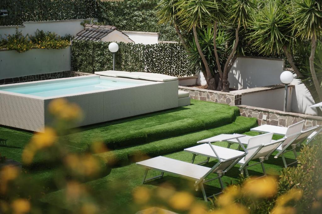 een achtertuin met een zwembad en witte stoelen bij Villa Nicole Vista Mare in Andrano