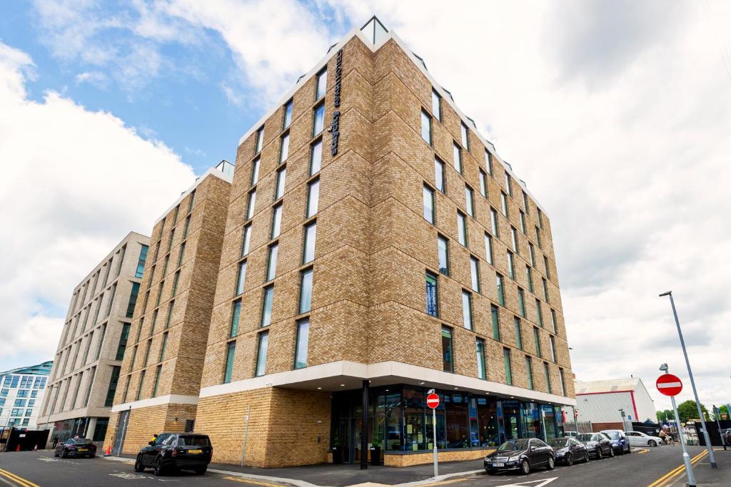 a tall brick building with cars parked in front of it at Staycity Aparthotels Manchester Northern Quarter in Manchester