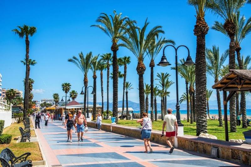 grupa ludzi spacerujących po chodniku z palmami w obiekcie Blue Ocean Apartment w mieście Torremolinos