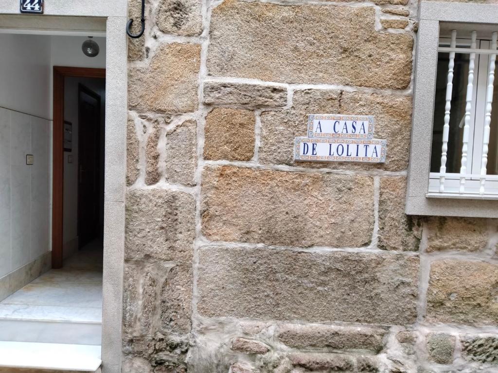 a sign on the side of a stone wall at A Casa de Lolita in Muros
