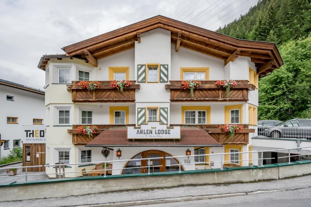 un bâtiment dans les montagnes avec des fleurs sur le balcon dans l'établissement Arlen Lodge Hotel, à Sankt Anton am Arlberg