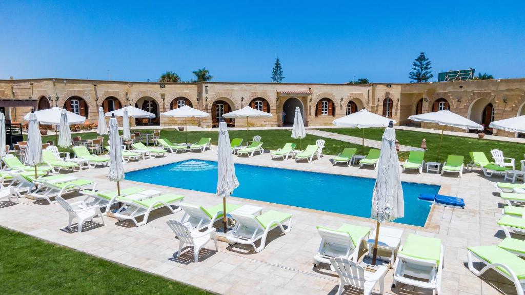 a resort pool with lounge chairs and umbrellas at Golden Lake Marina Hotel in El Alamein