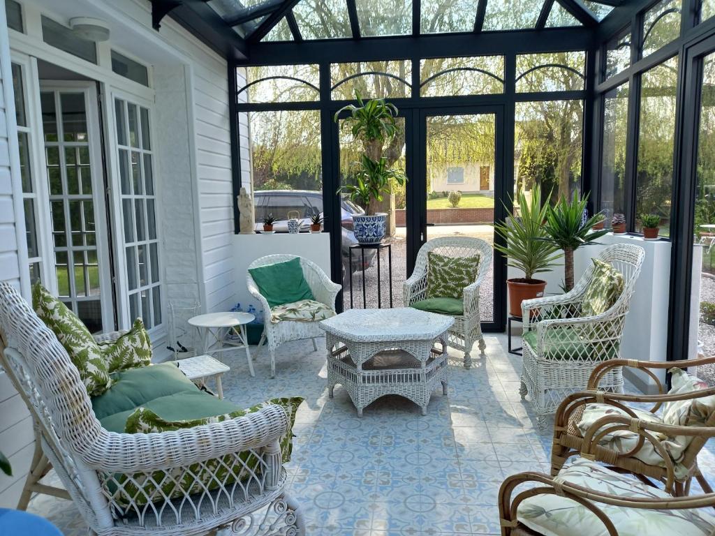 - une véranda avec des chaises et une table dans l'établissement villa marguerite 65 rue legout lesage 76260 ponts et marais, à Ponts-et-Marais