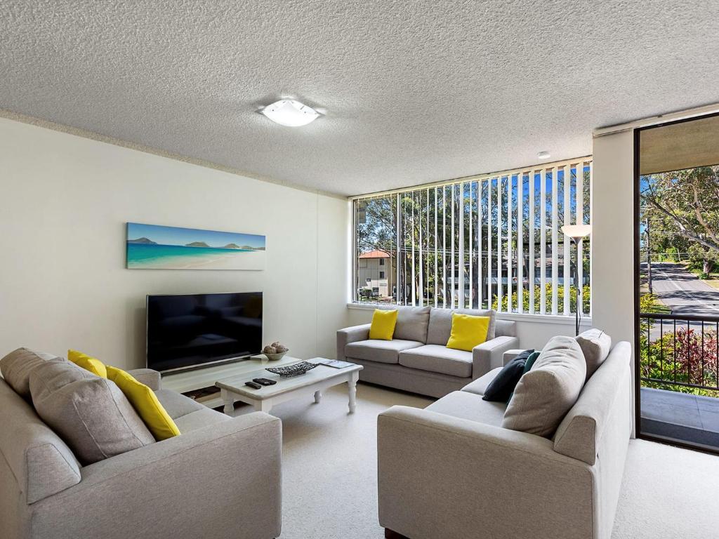 a living room with two couches and a television at Magnus Gardens 4 beautiful air conditioned unit with filtered water views and Wi-Fi in Nelson Bay