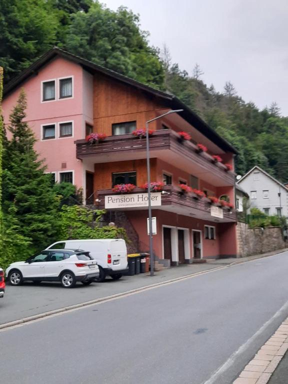 a building on the side of a street with cars parked in front at Pension Hofer in Bad Berneck im Fichtelgebirge