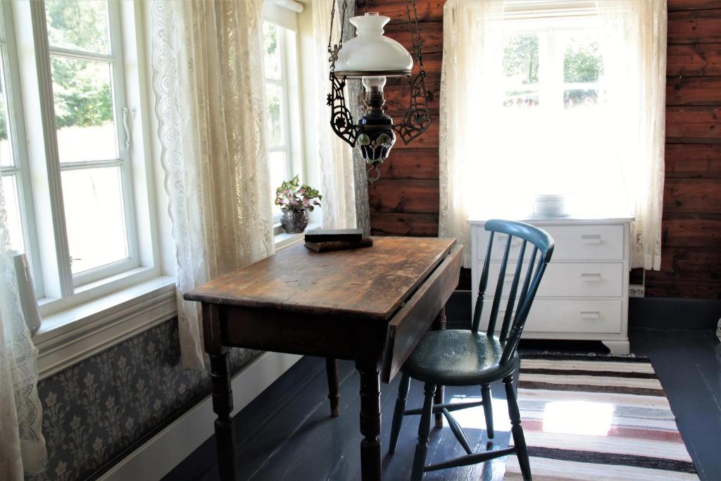einen Schreibtisch mit Stuhl in einem Zimmer mit Fenstern in der Unterkunft Lille Gjersdal - Et unikt opphold 100 år tilbake i tid in Farsund
