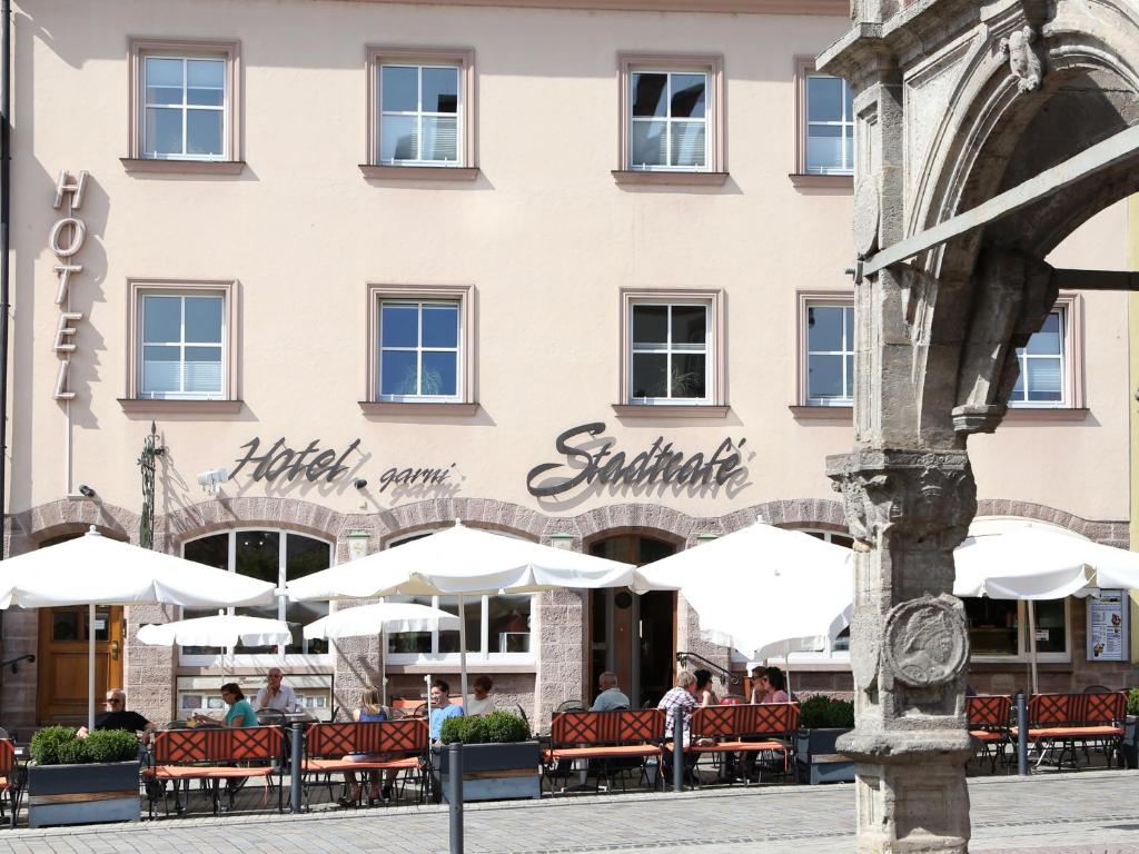a building with tables and umbrellas in front of it at Stadtcafé Hotel garni in Hammelburg