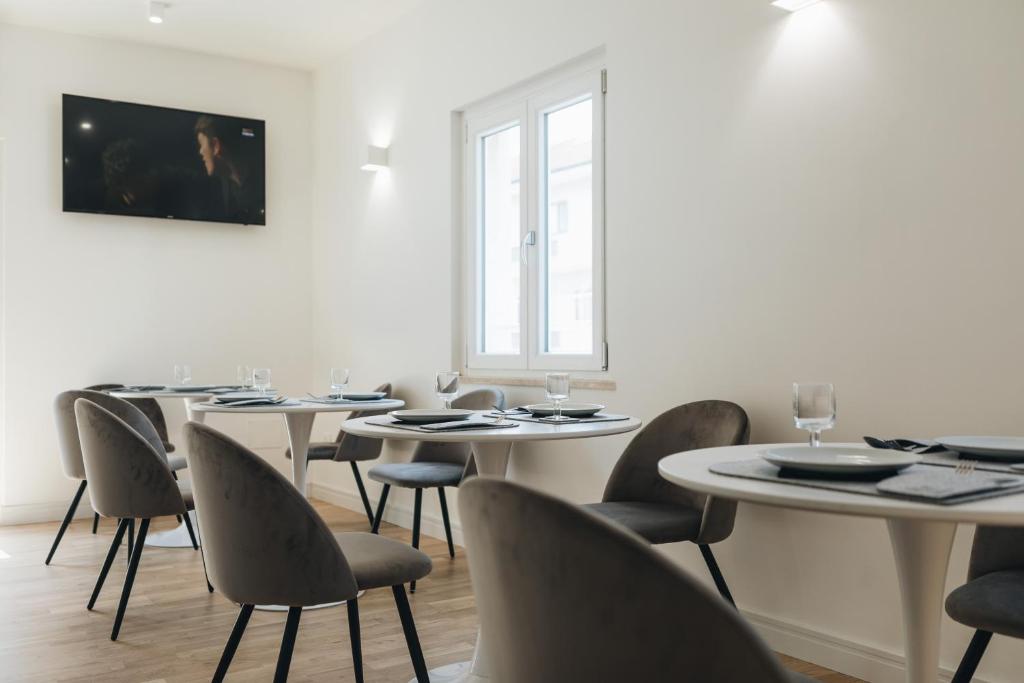 jadalnia z białymi stołami i krzesłami w obiekcie Centoquindici Rooms & Suite w mieście Montesilvano