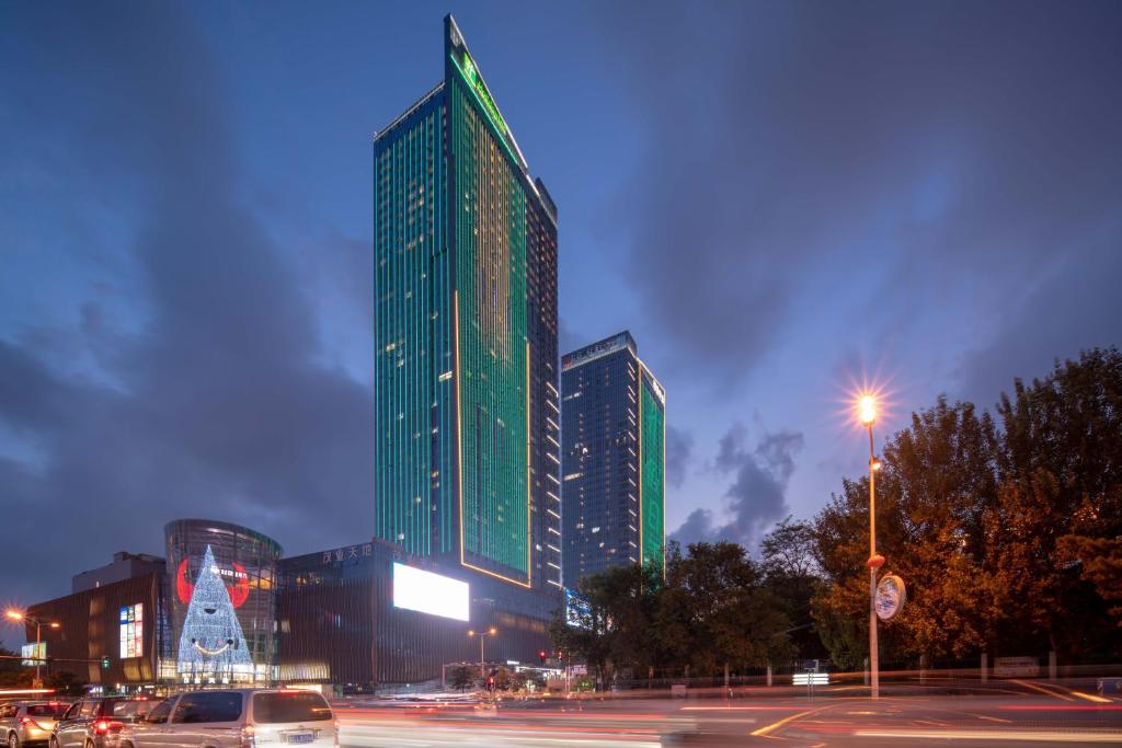 a tall green building with a christmas tree in front of it at Holiday Inn Qinhuangdao Haigang in Qinhuangdao