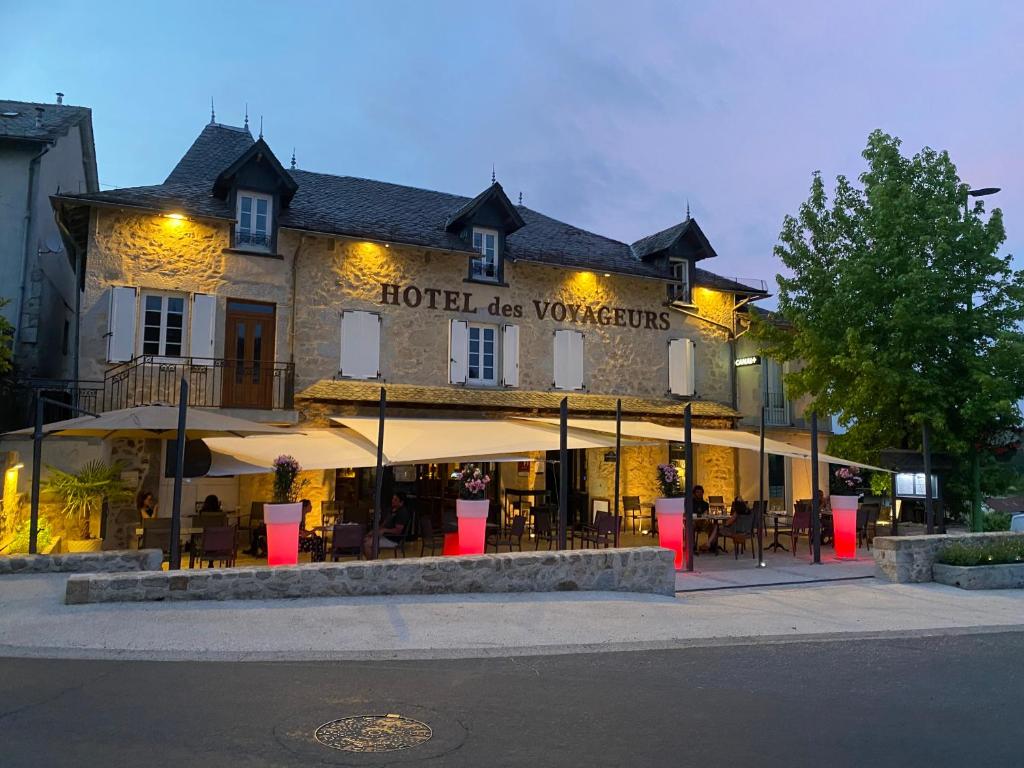 a hotel with tables and chairs in front of a building at Hotel Des Voyageurs in Le Rouget