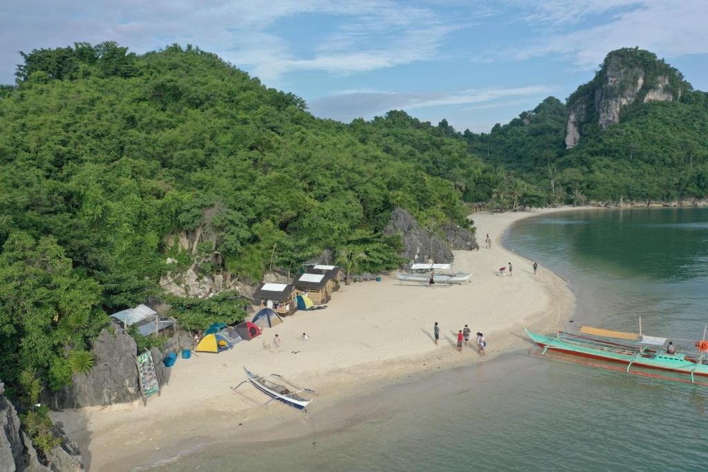 a beach with a group of people and a boat on it at Borawan Island Resort by Cocotel in Quezon