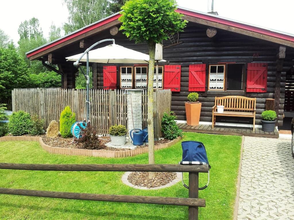 a log cabin with a bench and an umbrella at Haus Monika in Waldmünchen