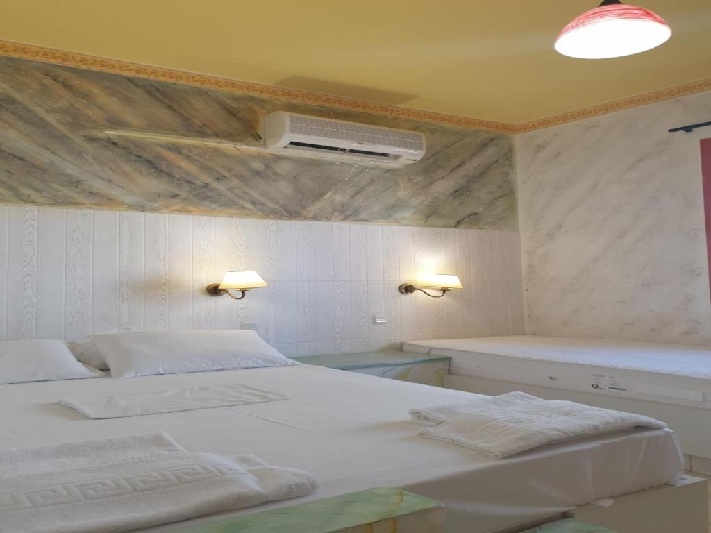 Biała sypialnia z 2 łóżkami i wentylatorem w obiekcie Room in Apartment - Spacious Room in Creta for 3 people, with Ac, Swimming Pool and Nature w mieście Hersonissos