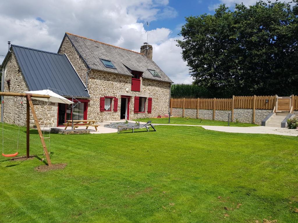 una casa de piedra con parque infantil en un patio en "La MAISON DE DANA" ENTRE ST MALO & MT ST MICHEL avec Piscine privative en Epiniac