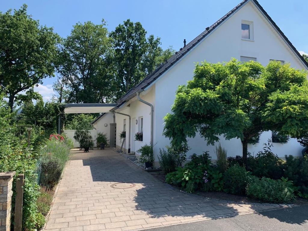 a white building with a tree next to a sidewalk at Ferienwohnung Schmitt in Lauf an der Pegnitz