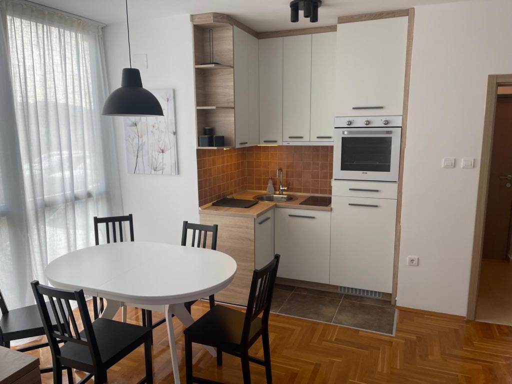 a kitchen with a white table and chairs and a kitchen with a sink at Apartman 12 Jelena Anžujska in Zlatibor