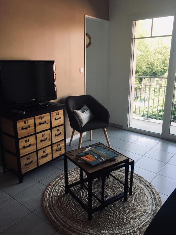 a living room with a tv and a chair and a coffee table at Colibri Appart&#39; T2 au coeur du Bassin d&#39;Arcachon in Gujan-Mestras