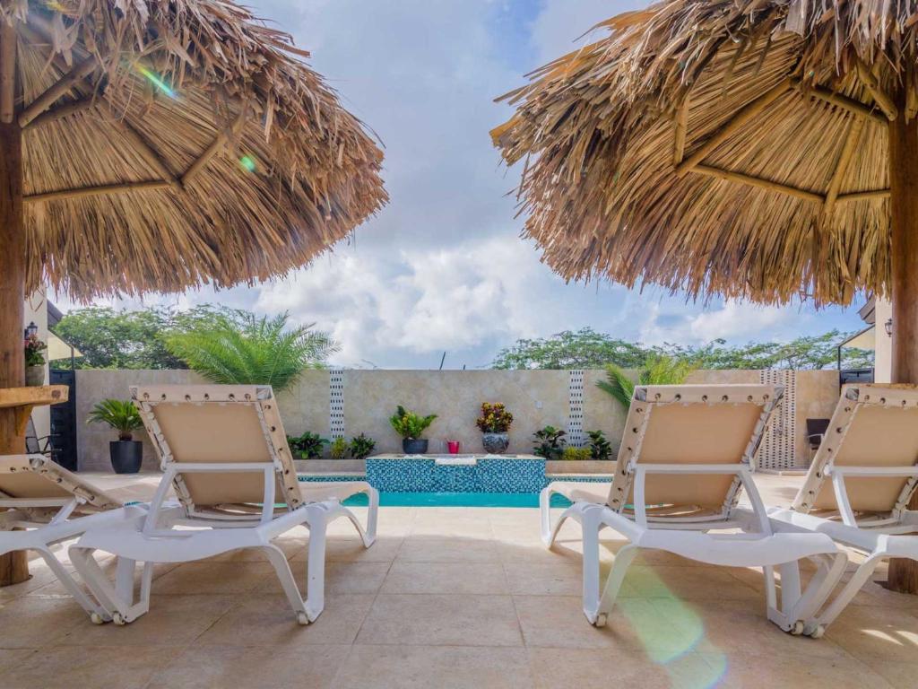 a patio with two chairs and two umbrellas at Golden Villas in Palm-Eagle Beach