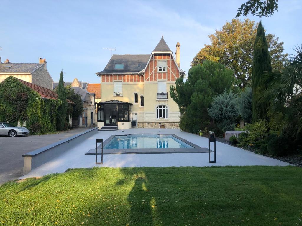 a house with a swimming pool in front of a yard at Le Pavillon de Nathalie in Isles-sur-Suippe