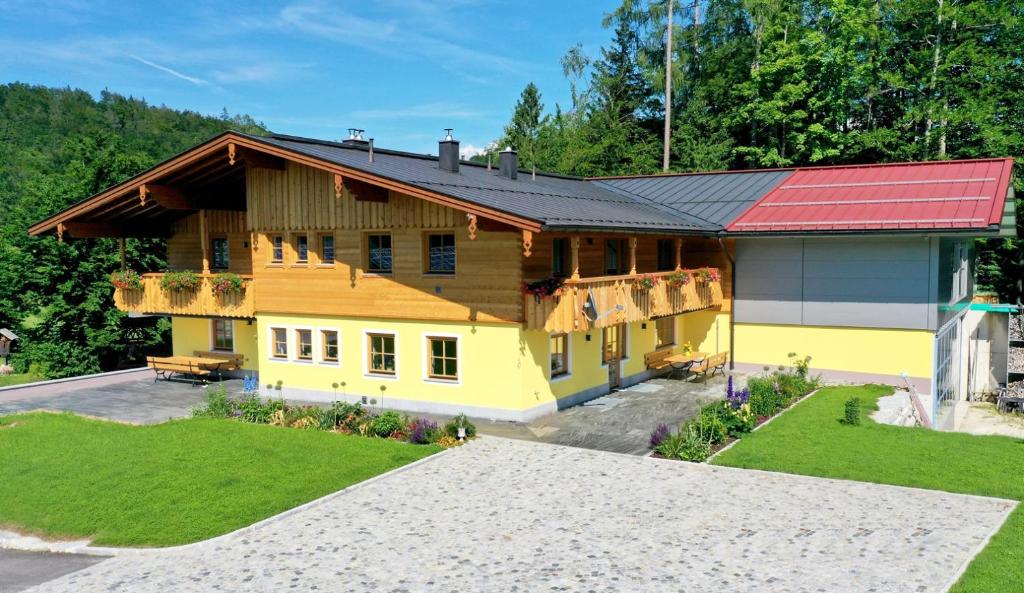 ein großes gelbes Haus mit rotem Dach in der Unterkunft Ferienwohnung Josef Koll in Marktschellenberg
