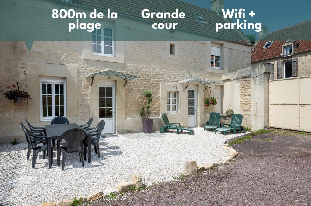a patio with a table and chairs in front of a building at L'escalier rouge - Maison rénovée avec cour in Luc-sur-Mer