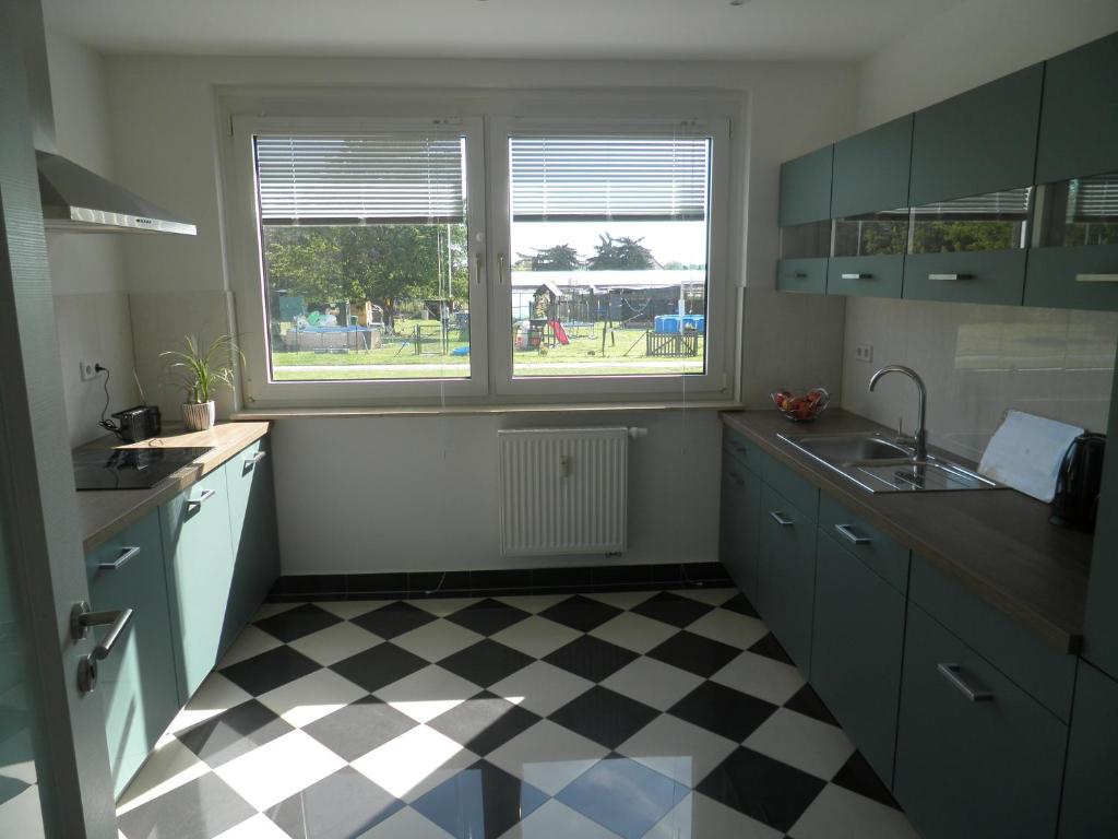 a kitchen with blue cabinets and a checkered floor at Rockys Ferienwohnung in Zwenkau
